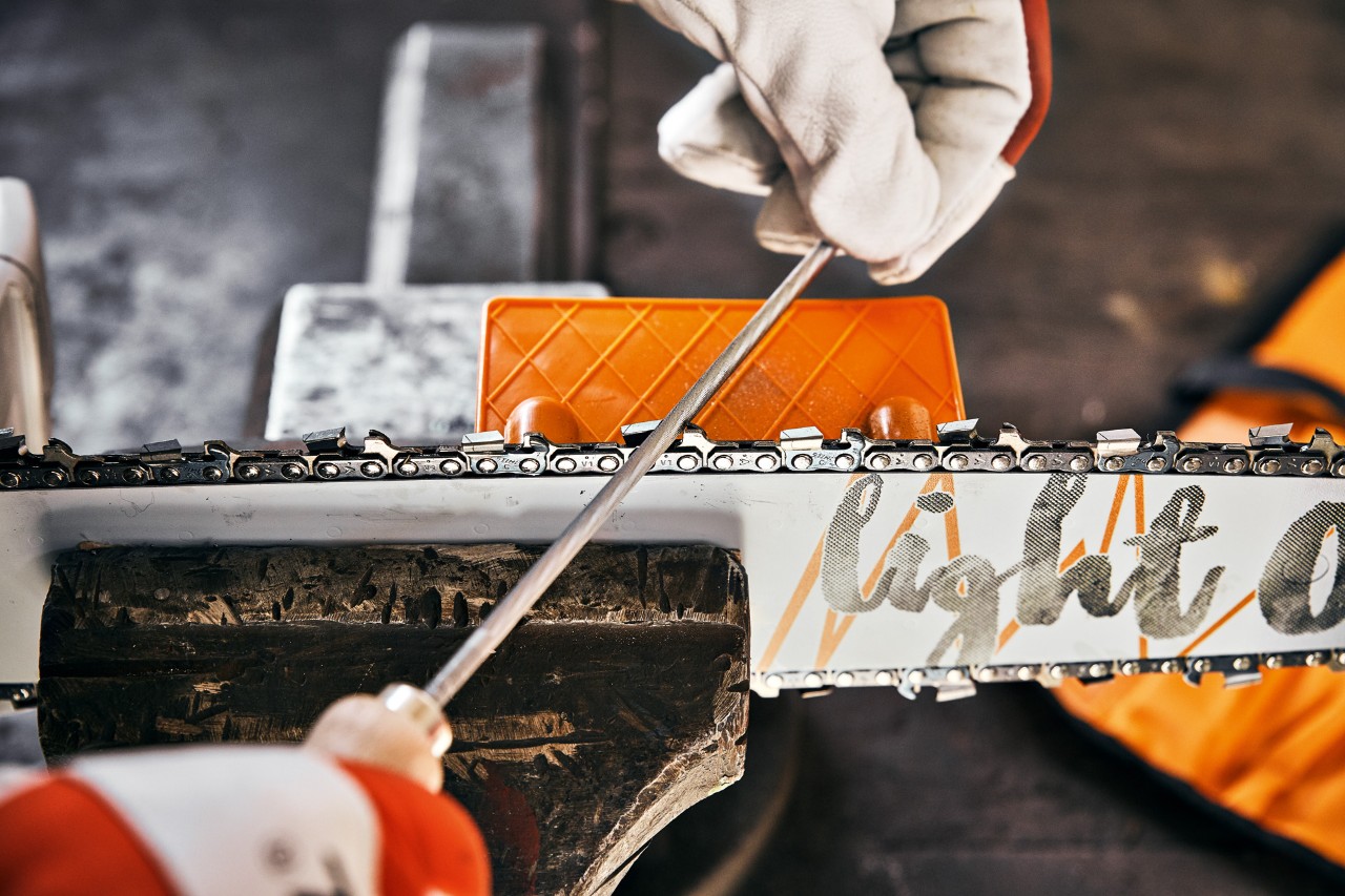 A chainsaw tooth being sharpened with a round file and a STIHL file angle plate