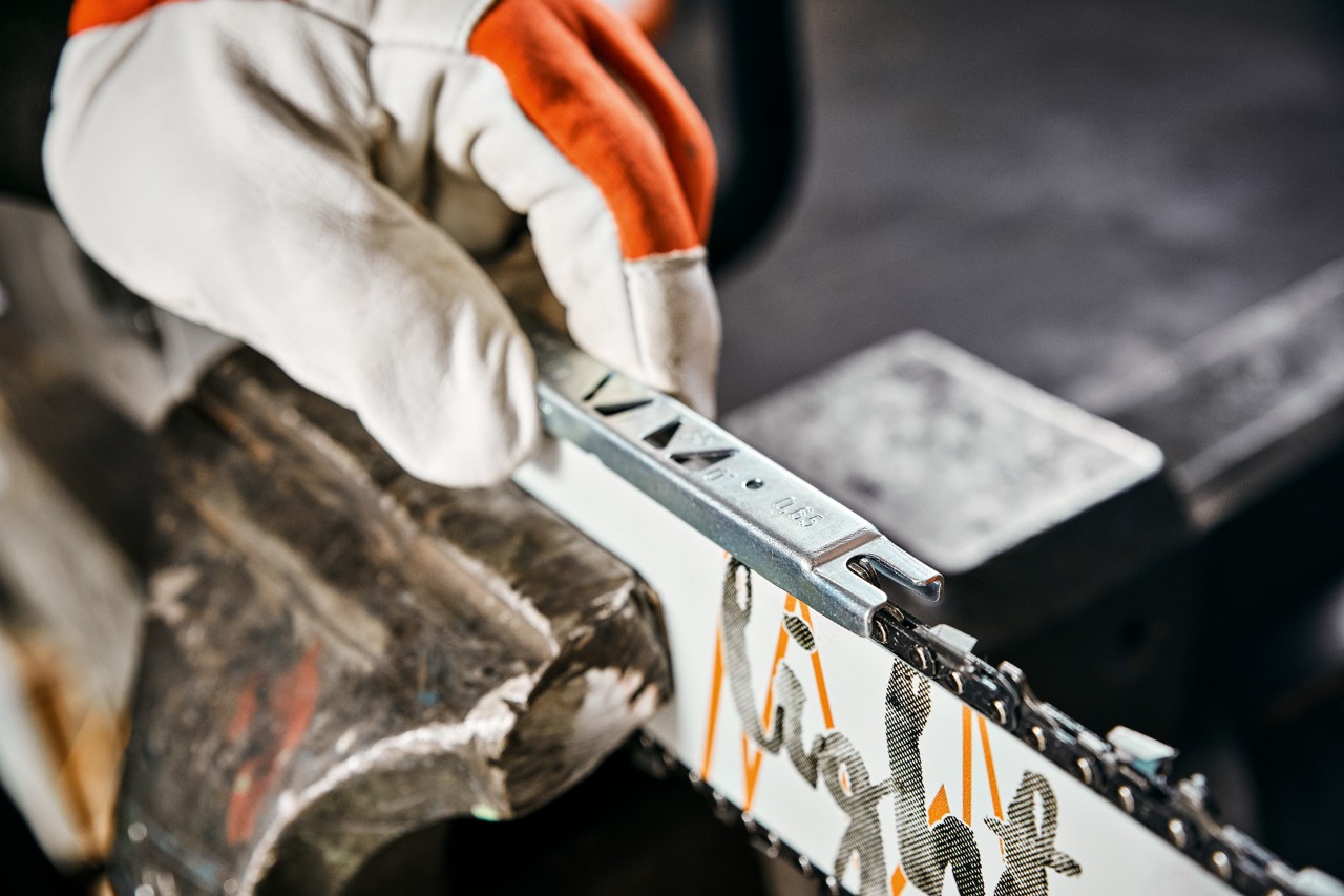 Close-up of a filing gauge being used to check the depth gauge setting on a chainsaw