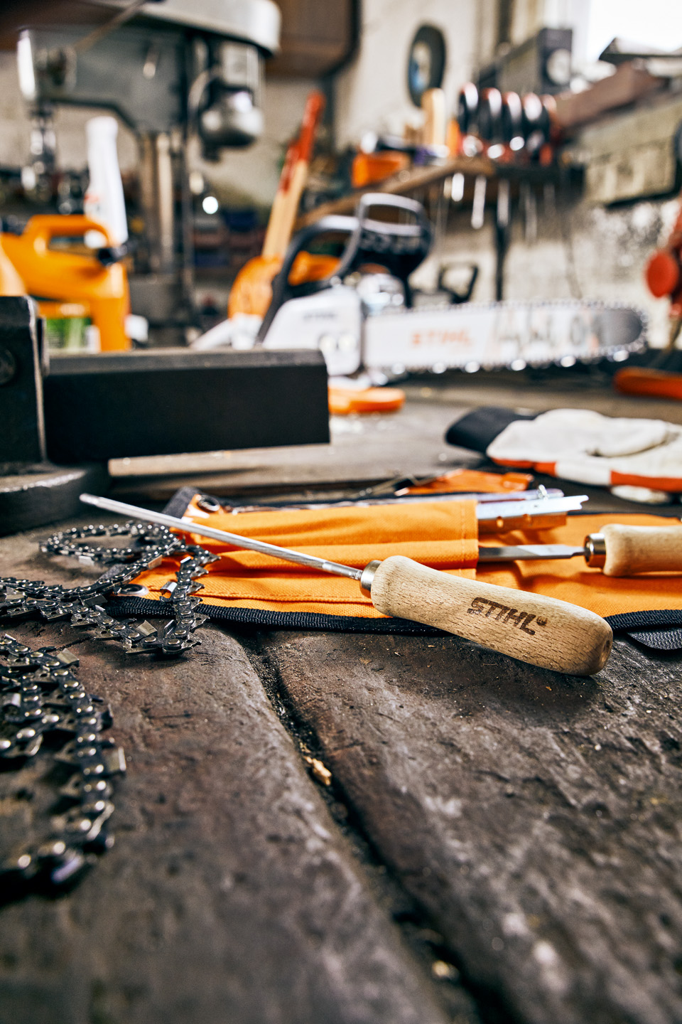 Close-up of STIHL chainsaw files and chain on a workbench with other tools visible in the background