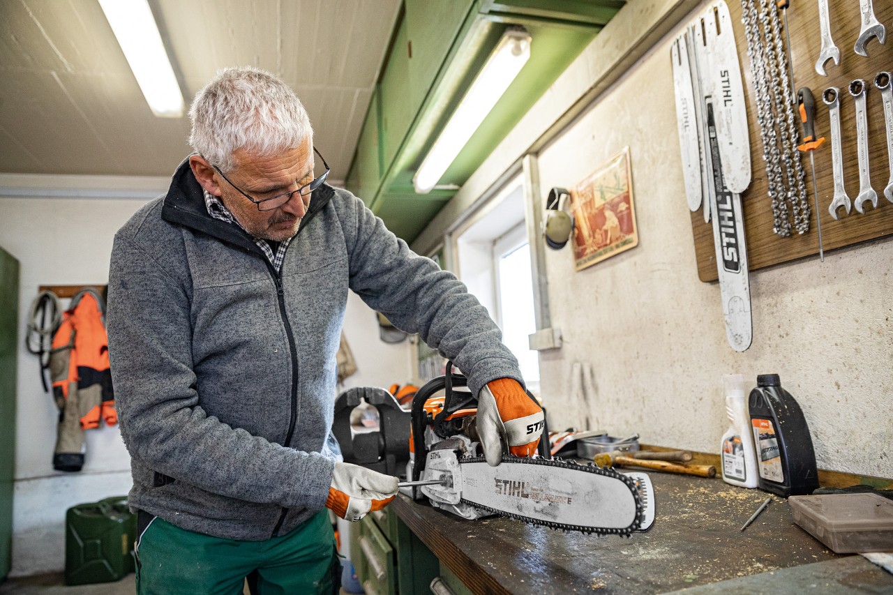 A man in the process of tightening a STIHL chainsaw chain in a workshop
