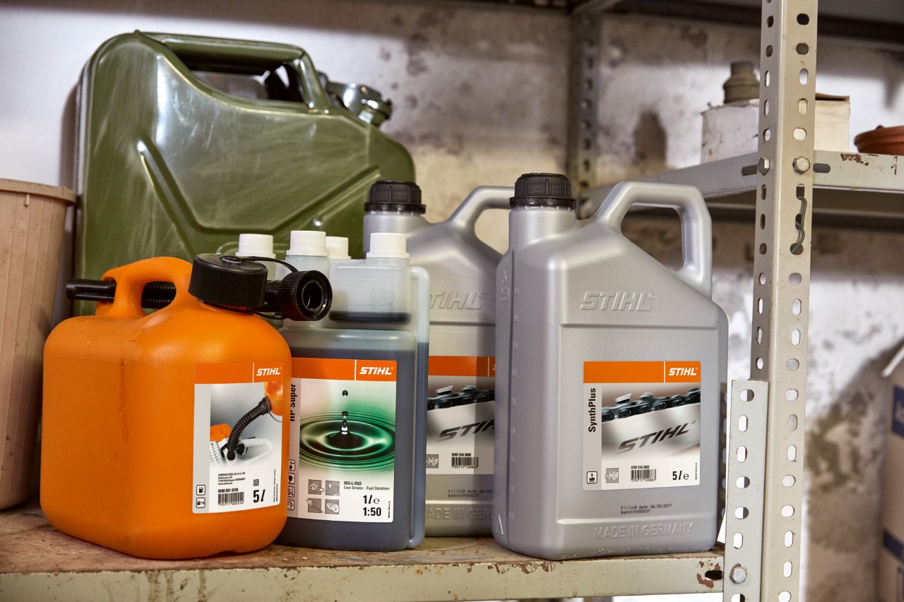 A collection of canisters including a bottle of STIHL HP Super 2-stroke engine oil and an orange combination canister
