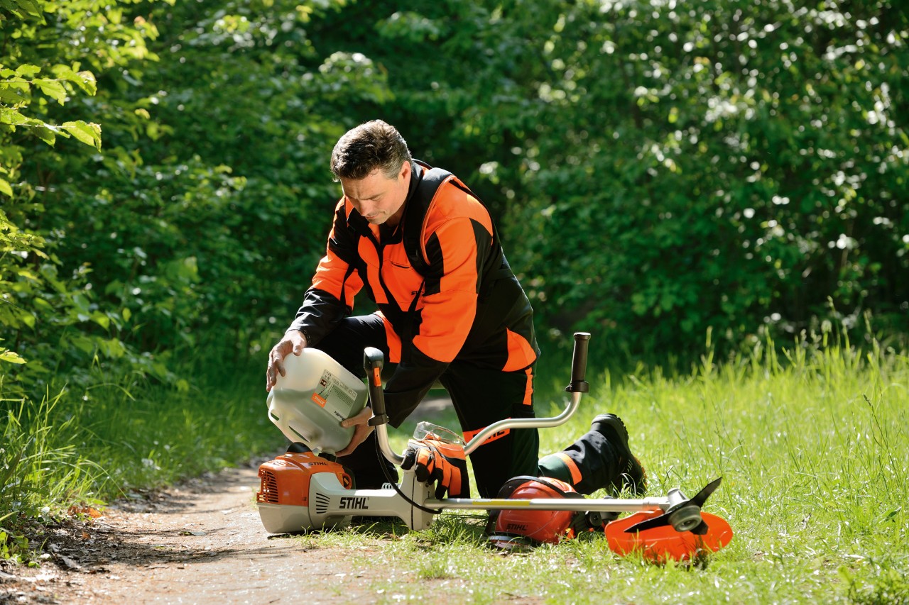 A man refuels a STIHL brushcutter with a mixture of gasoline and oil.