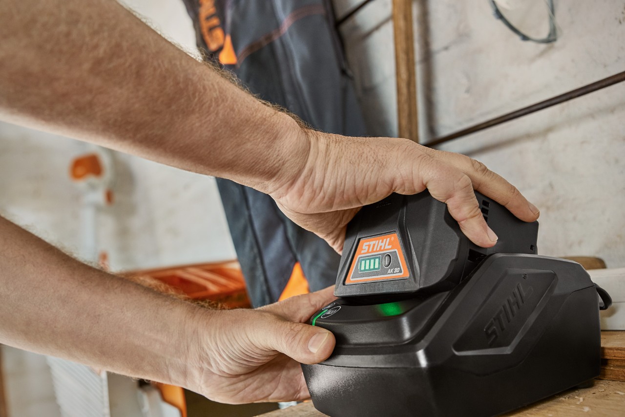 A person removing a STIHL AK 30 battery from the charger