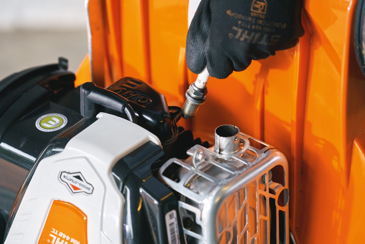 Spark plug being removed from a STIHL RM 448 T-C petrol lawn mower