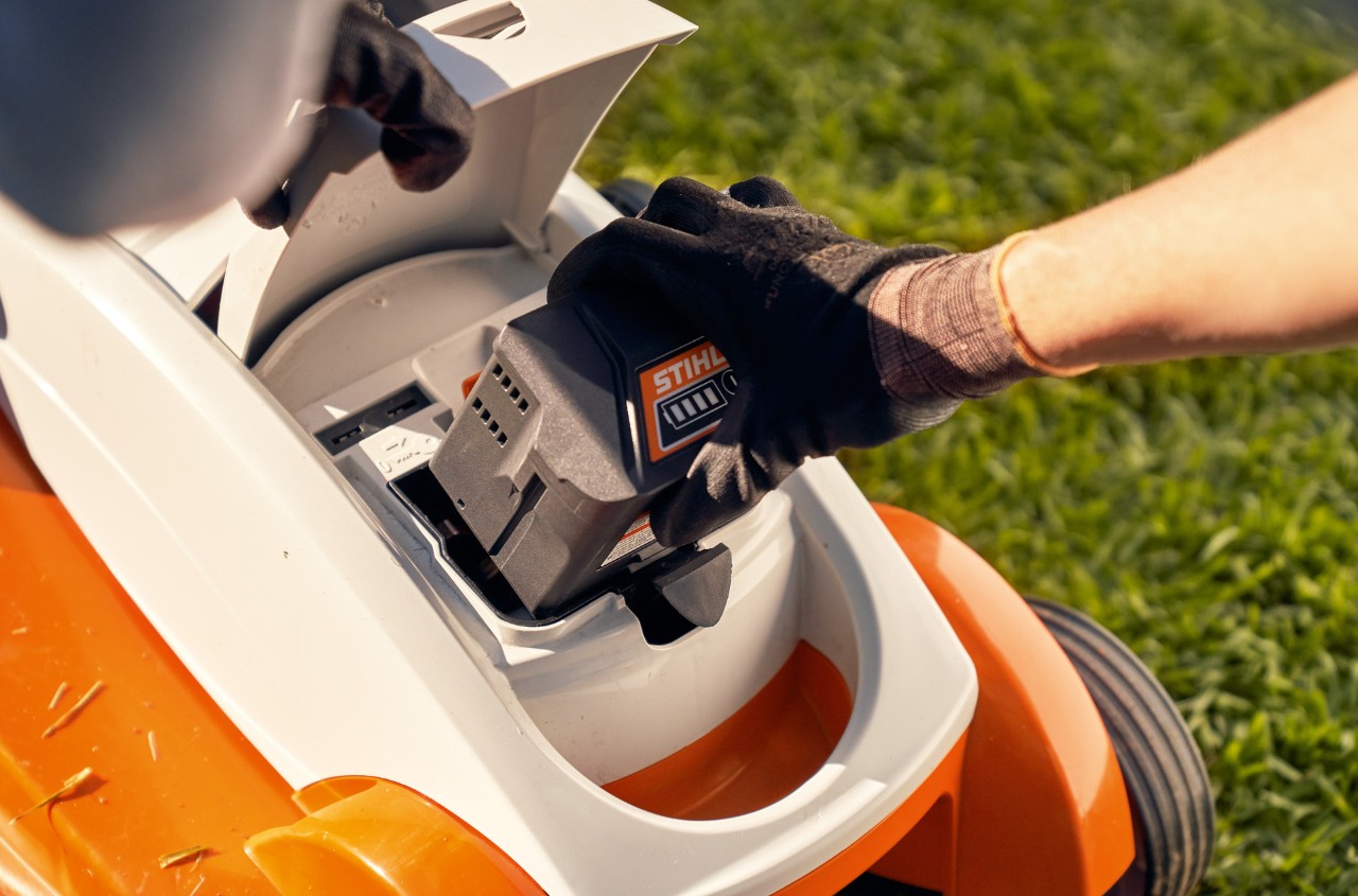 Person removes the battery from a STIHL RMA 339C cordless lawn mower for winter storage