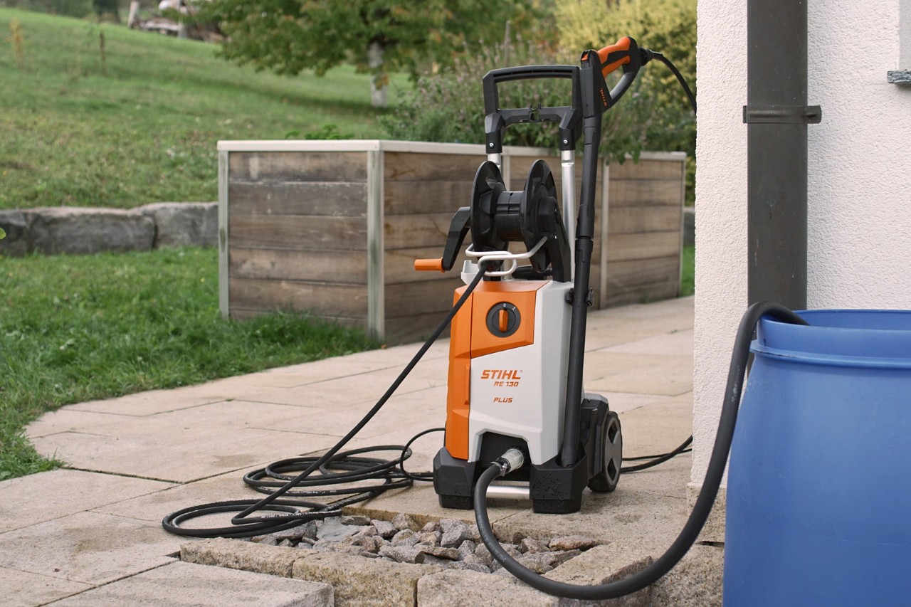 A connected-up STIHL RE 130 PLUS high-pressure cleaner on a terrace, ready for use 