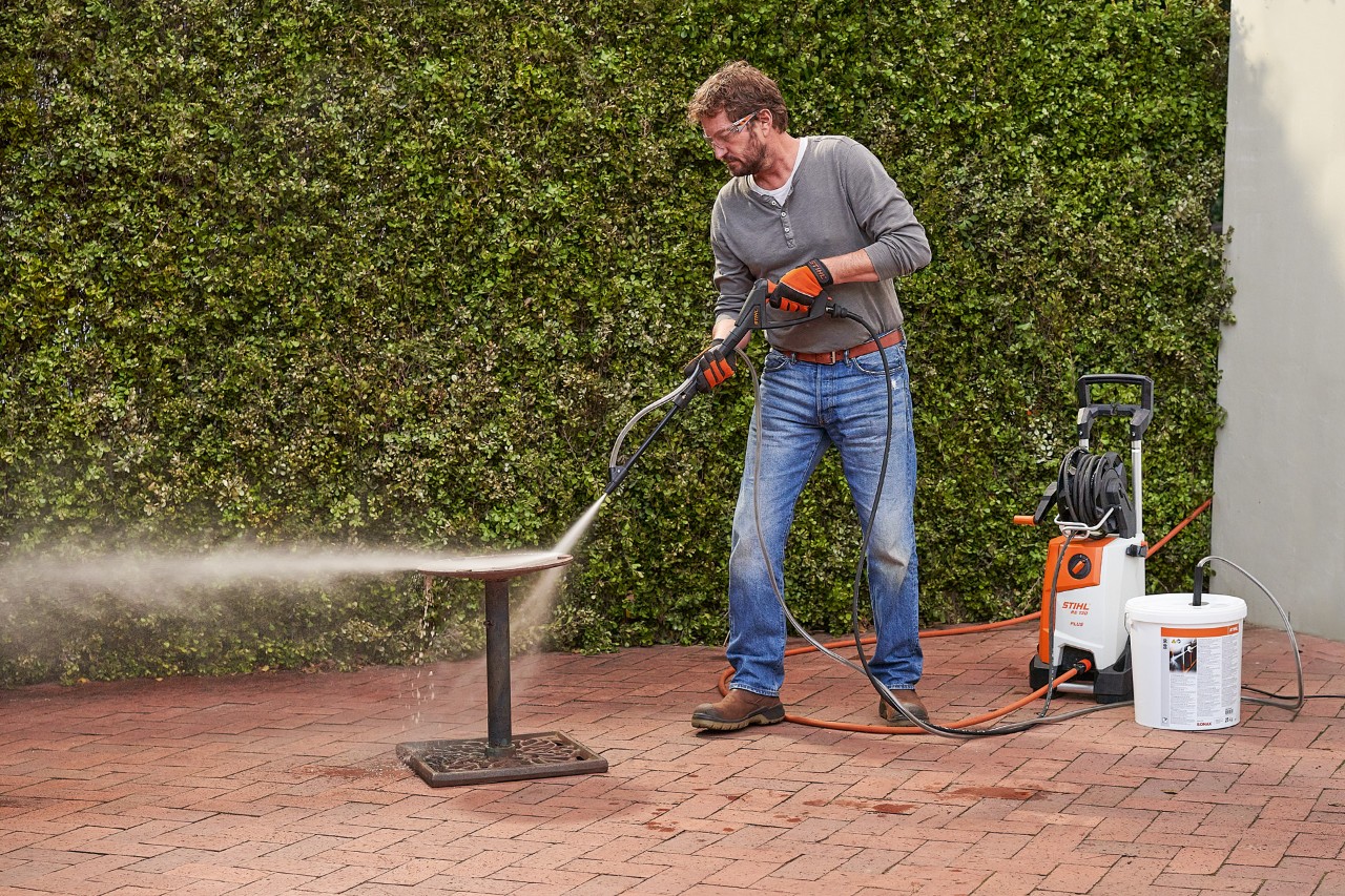 A man in front of a garage wet sandblasting using the STIHL RE 130 PLUS high-pressure washer