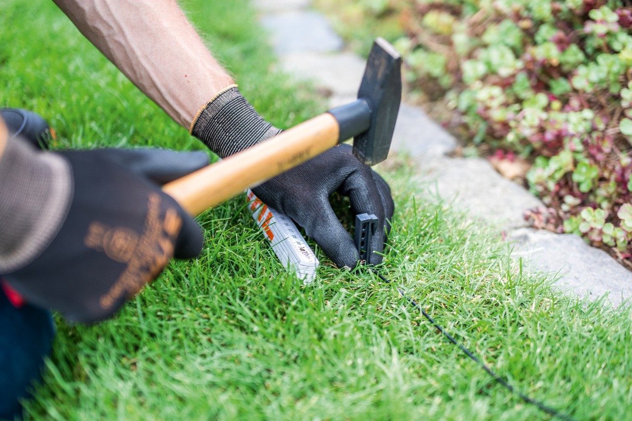 Perimeter wire for a STIHL iMOW® 422 robotic mower being installed along the edge of a lawn