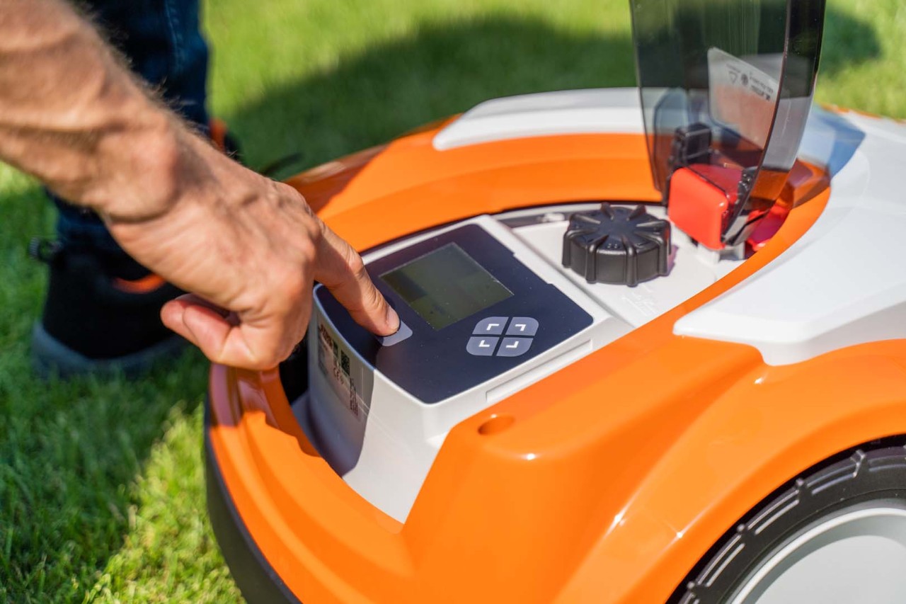 The control panel of a STIHL iMOW® 422 robotic mower as someone presses a button on it