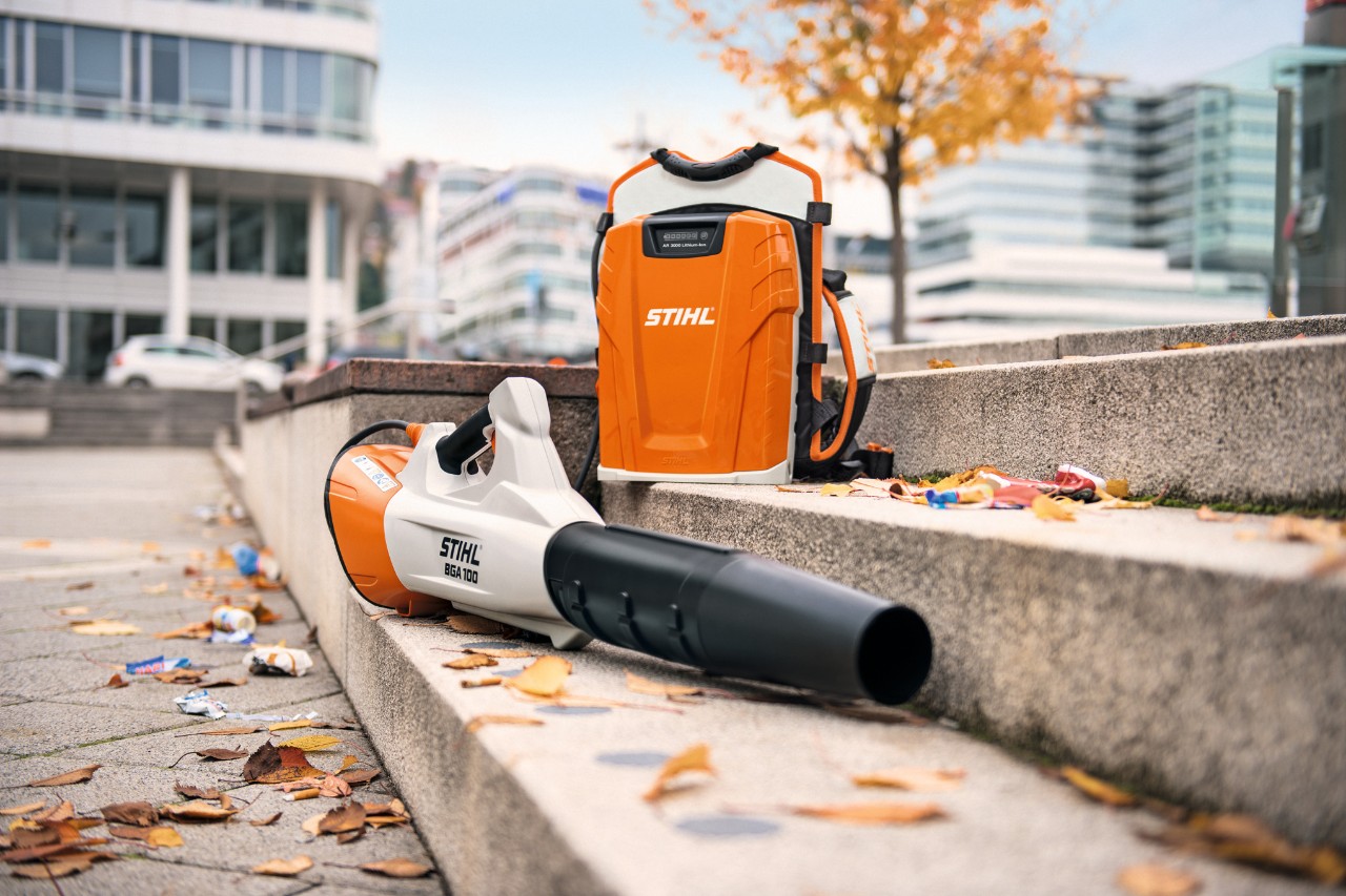 The STIHL BGA 100 cordless leaf blower and the STIHL AR 3000 L professional backpack battery positioned on a stone staircase with a few leaves