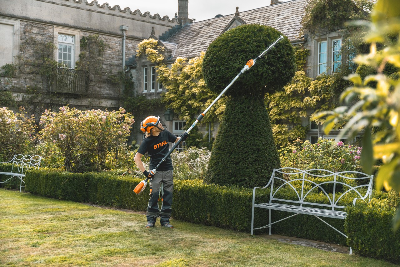 Andrew Wain trims a sculpted bush with a battery hedge trimmer