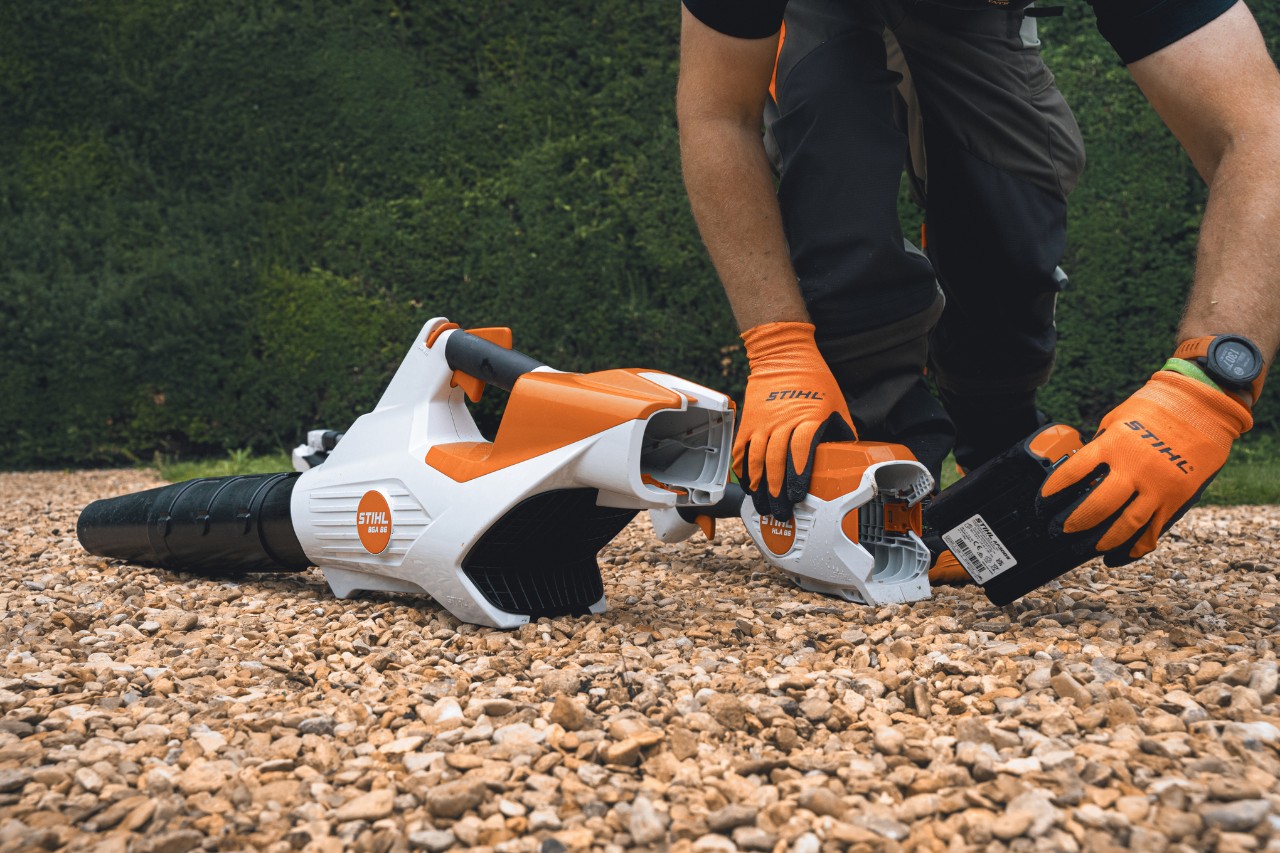 A professional changes the battery of their STIHL battery leaf blower in front of the hedge at Bathurst Estate
