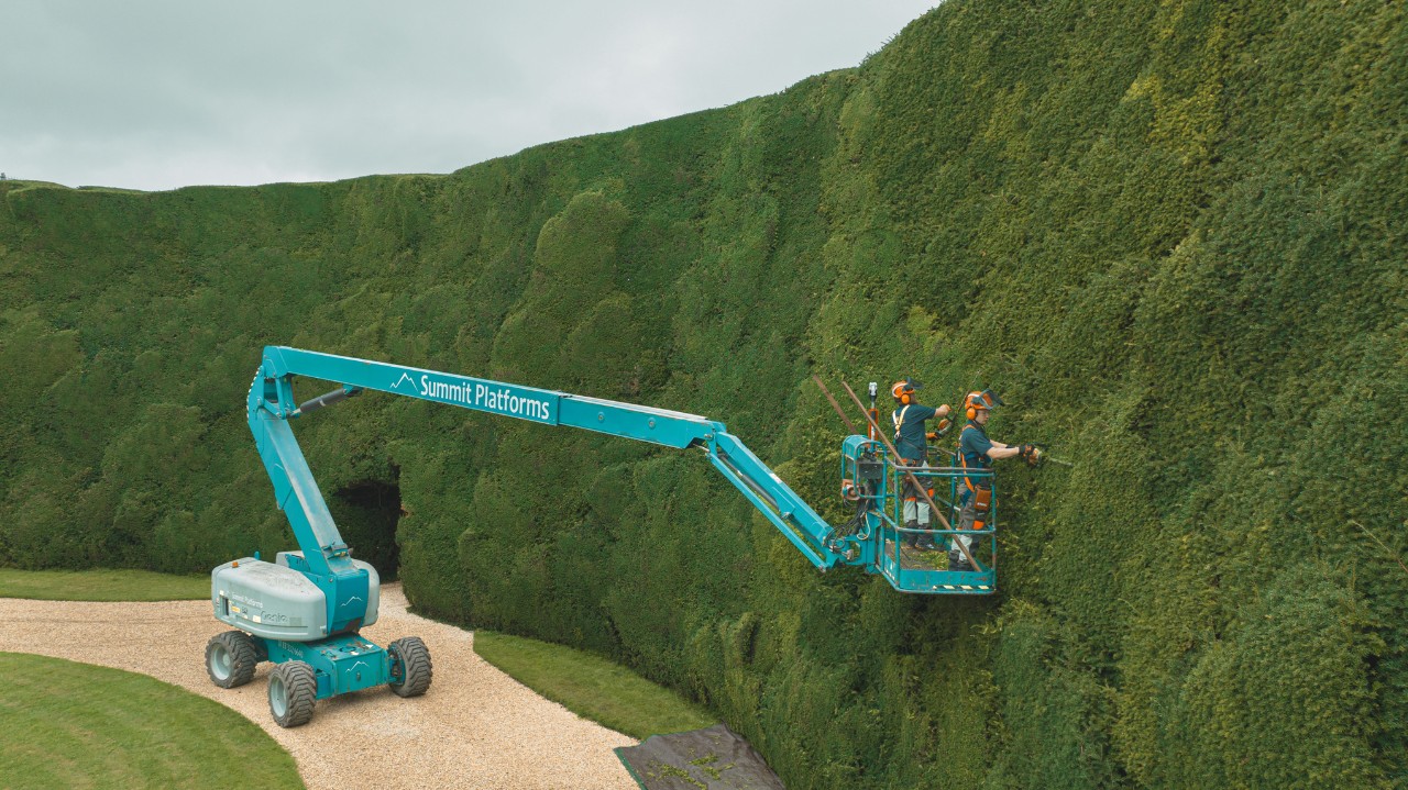 Two professionals trim the high hedge at Bathurst Estate on a lifting platform