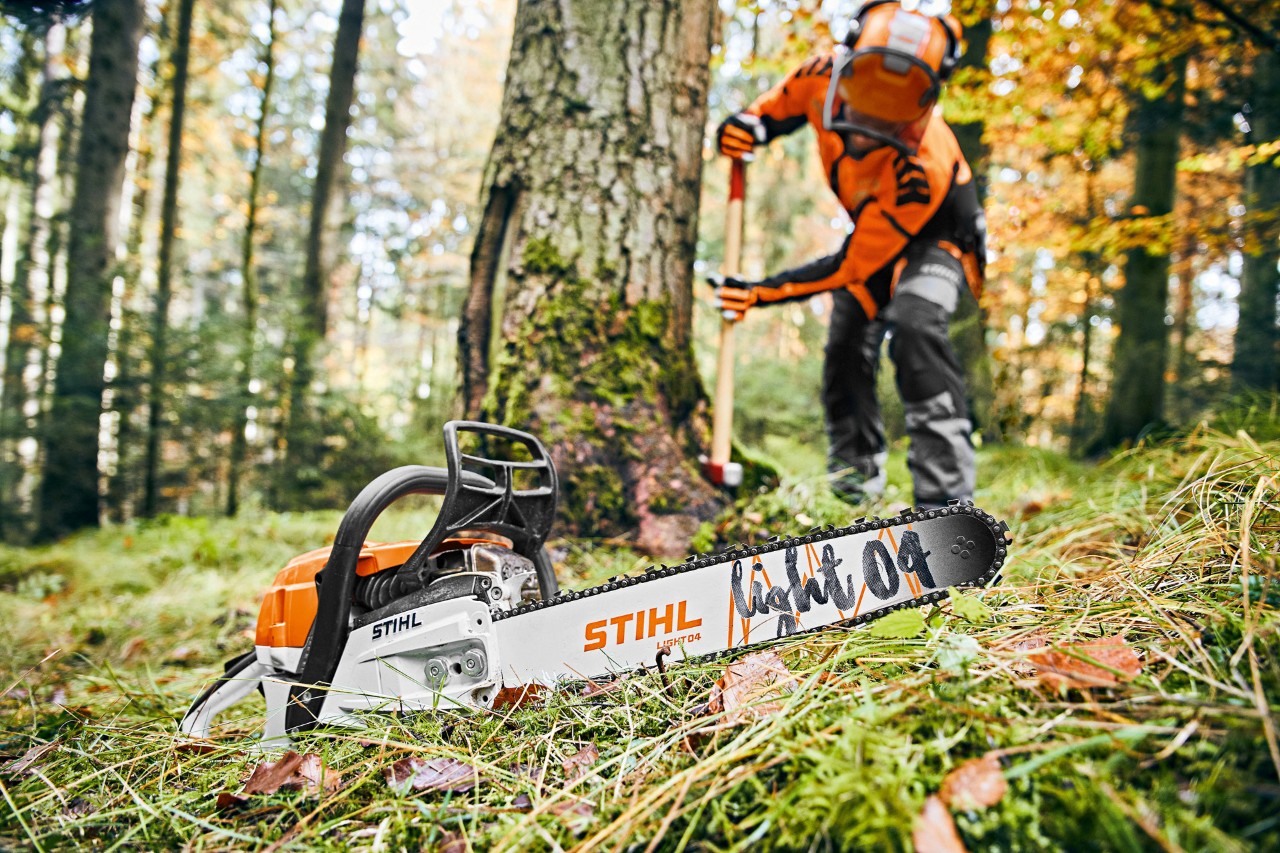 A man wearing safety gear by a tree, with a STIHL MS 261 C-M petrol chainsaw with Light 04 guide bar in the foreground