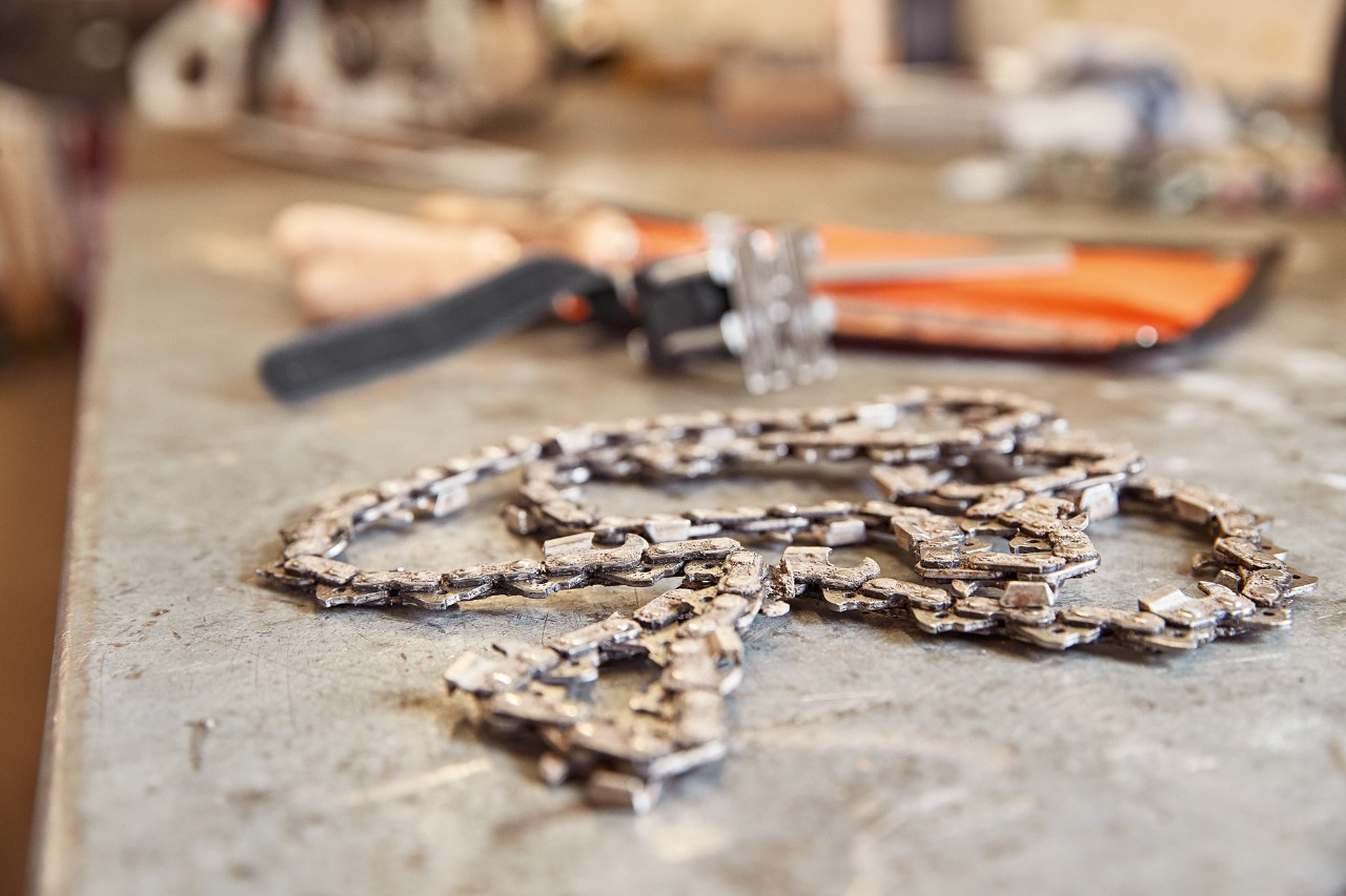 A STIHL saw chain beside a tool on a workbench