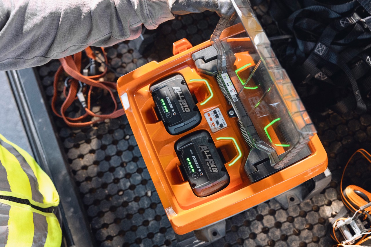 Someone holding an ALLPRO battery in front of a truck