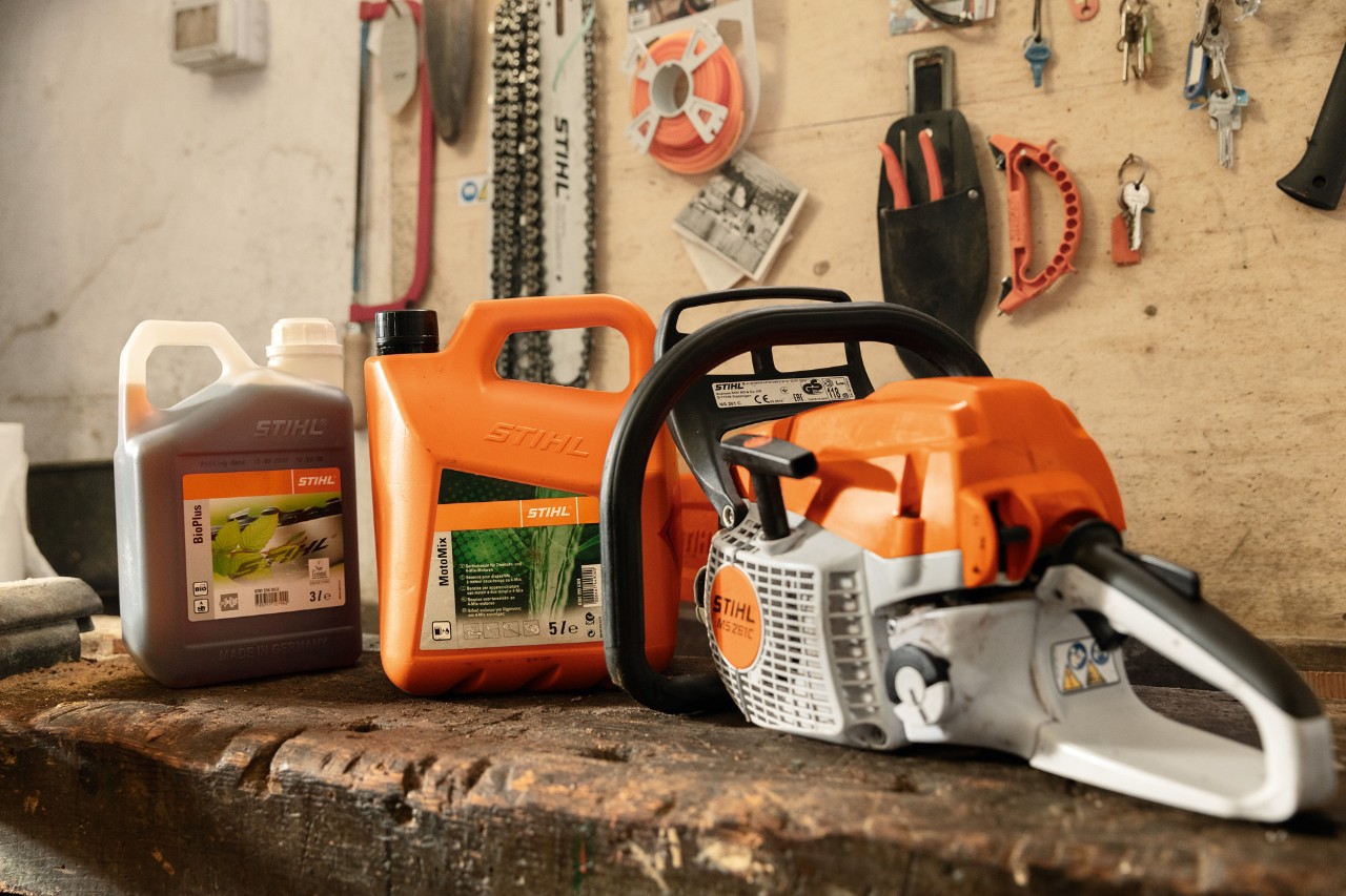 STIHL MS 261 C-BE chain saw with toolless fuel tank cap next to MotoMix and BioPlus
