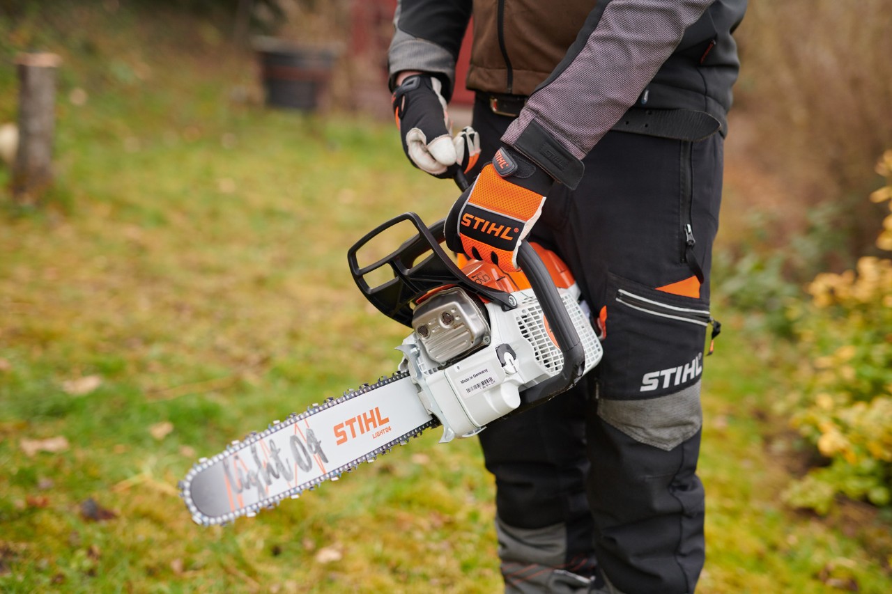 A man in protective equipment holding a STIHL petrol chainsaw with ElastoStart and Light 04 guide bar