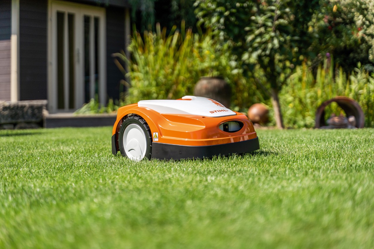 A STIHL iMOW® RMI 422 robot mower on a green lawn in front of a house