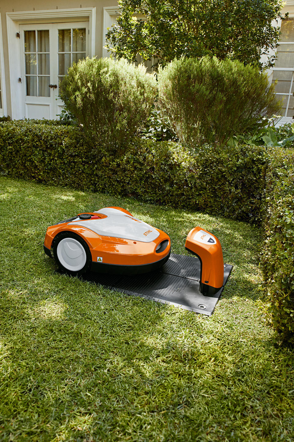 A STIHL iMOW® RMI 632 robot mower in its charging station in a garden.