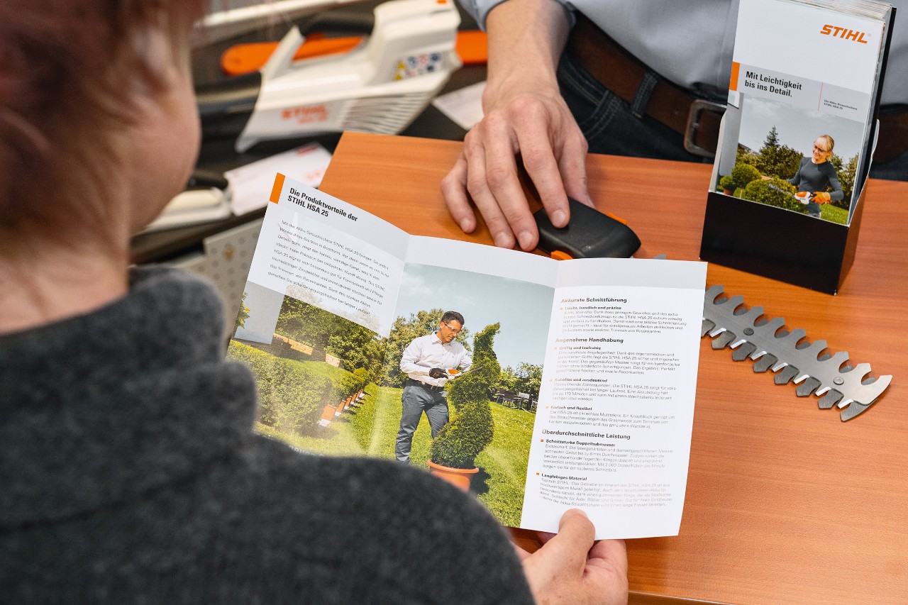 A person reading about the STIHL HSA 25 product benefits in a brochure
